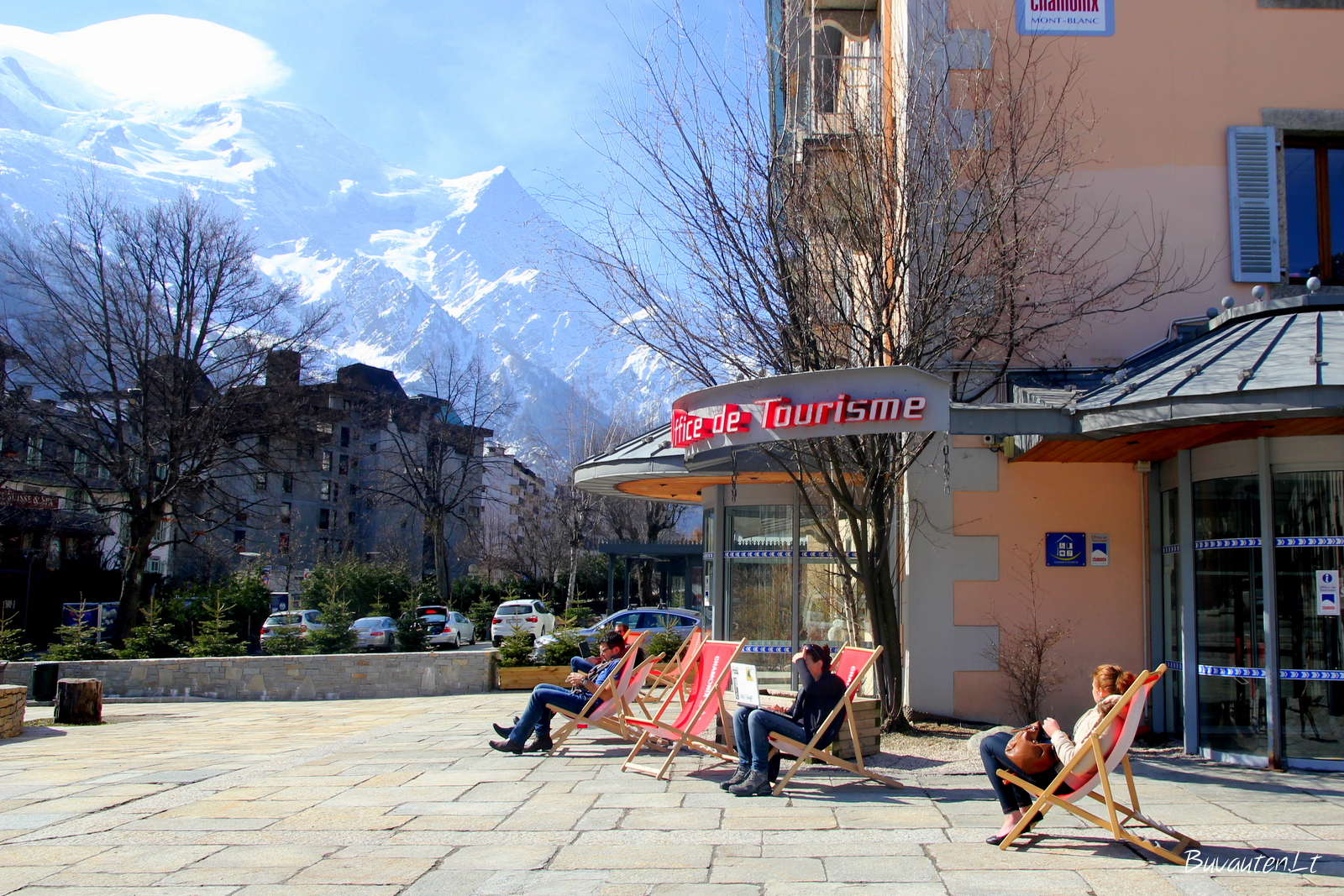 Turistai šalia turizmo biuro gaudo pavasario saulę